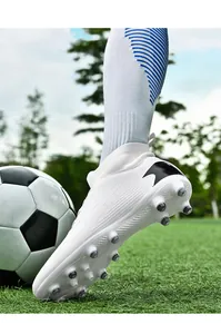 Primer plano de botas de fútbol blancas de caña alta con tacos AG en césped