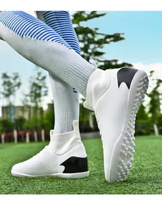 Vista detallada de botas de fútbol de caña alta blancas con detalles negros en césped