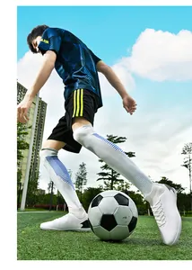 Primer plano de botas de fútbol blancas de caña alta en un campo durante el entrenamiento