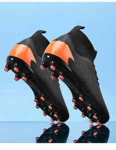 Detalle de botas de fútbol de caña alta negras y naranjas con suela de tacos para césped