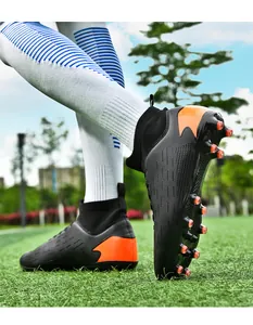 Detalle de botas de fútbol de caña alta negras y naranjas con tacos de goma