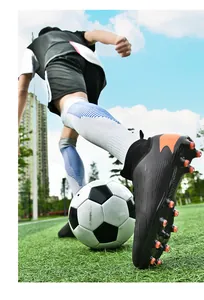 Primer plano de acción de botas de fútbol negras de caña alta con tacos naranjas