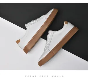 Κορυφαία άποψη λευκών ανδρικών casual sneakers με καφέ σόλα από καουτσούκ σε αντίθεση