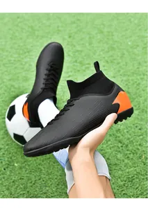 Primer plano de mano con botas de fútbol negras de bota alta en campo de césped verde