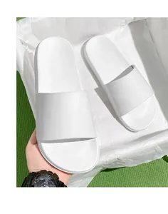 Gros plan de claquettes blanches minimalistes à semelle souple dans une boîte d'emballage.
