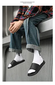 Détail des claquettes d'été noires minimalistes portées avec des chaussettes blanches