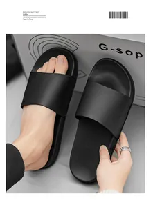 Détail de claquettes noires à semelle souple portées et tenues par une main d'homme.