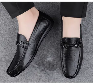 Close-up of black leather men's loafers with metal buckle on a gray surface