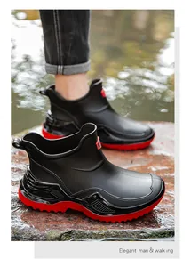 Detailed view of waterproof low-top rain boots with thick red sole on wet surface
