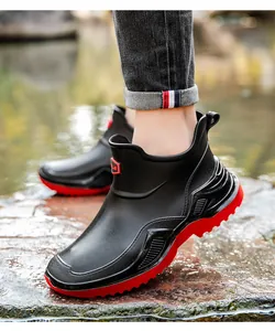 Stylish black waterproof ankle rain boots with thick red non-slip soles for outdoor use.