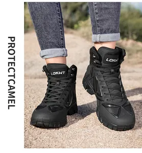 Close-up of black mid-cut tactical hiking boots worn on outdoor sandy ground.