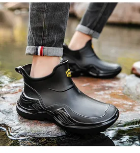 Close-up of black short waterproof rain boots with thick soles on a rocky river bank