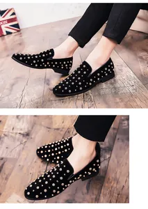 Detailopname van zwart suède herenloafers met gouden spikes op houten vloer