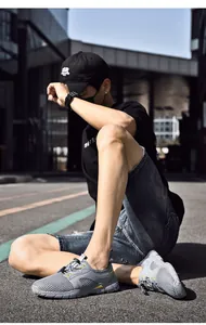 Close-up van grijze ademende mesh sneakers gedragen door een model op een stadsstraat