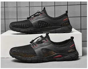 Detail van ademende zwarte mesh lage sneakers voor heren met opvallende rode accenten.