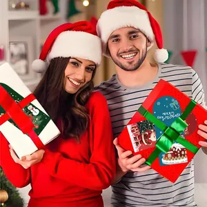 Tarjetas de felicitación navideñas en cajas de regalo sostenidas por una pareja feliz.