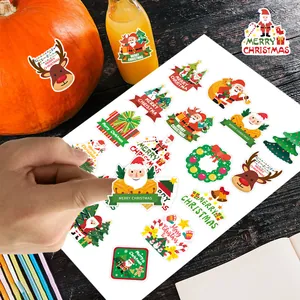 Détail macro d'une main décollant des autocollants de Noël festifs d'une feuille