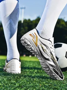 Gros plan de chaussures de football blanches avec semelle turf sur terrain en herbe.