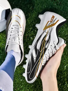 Gros plan de chaussures de football blanches avec motif vagues dorées et crampons