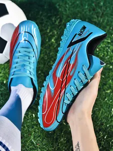 Gros plan détaillé de chaussures de football bleues et rouges avec motif flamme sur gazon