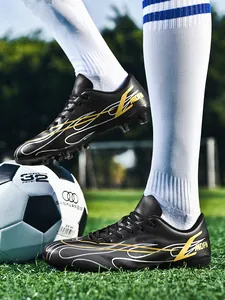 Gros plan de chaussures de football basses noires avec graphismes jaunes sur herbe