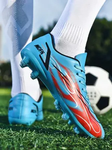 Vue détaillée de chaussures de football bleues avec motif de flammes sur terrain en herbe