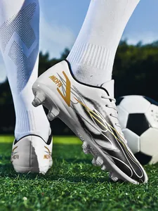 Détail de la vue latérale de chaussures de foot blanches avec motifs dorés sur herbe