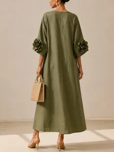 Back view of olive green linen dress featuring 3D floral sleeve appliqués