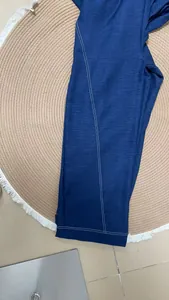 Detail of blue cotton linen jumpsuit showing white contrast stitching and texture.