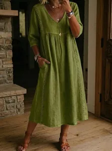 Detail showing the V-neck and lace trim of the green cotton linen dress.