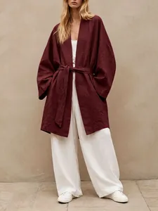 Full-body view of a burgundy oversized tie-waist cardigan worn by a model in a minimalist setting.
