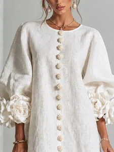 Close-up of 3D floral cuffs and textured buttons on a white linen lantern sleeve dress