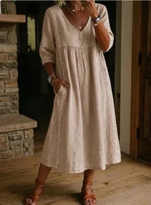 Detail of loose V-neck cotton linen dress with delicate white lace trim and pockets.