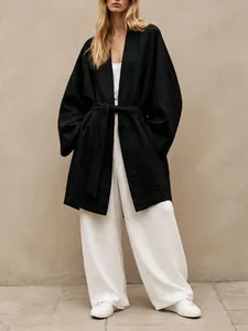 Model wearing a black loose-fitting belted kimono cardigan with white wide-leg trousers