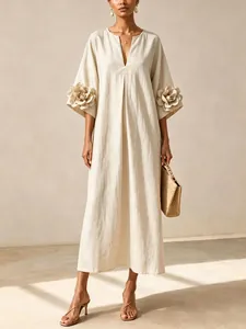 Detailed view of the oversized 3D flower applique on the sleeves of a beige linen dress
