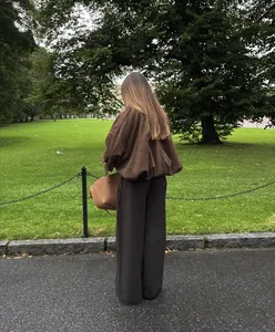 Back view of a stylish brown suede aviator jacket with batwing sleeves in a park