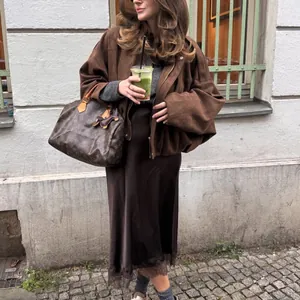 A stylish woman wears a brown suede oversized aviator jacket in a street setting