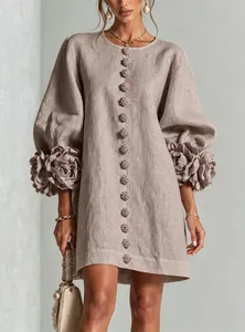 Detailed view of 3D floral appliqués on lantern sleeves of a taupe linen dress