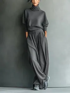 Detail showing the fabric texture and loose fit of the grey turtleneck and trousers set.