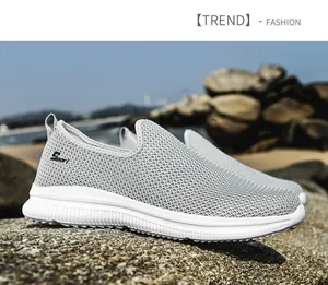 Close-up detail of grey breathable fly-woven mesh slip-on sneakers on a rocky outdoor beach