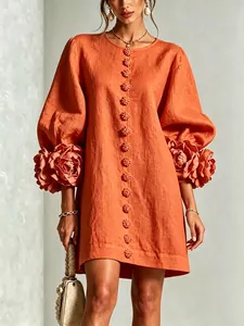 Close-up of 3D floral cuffs and lantern sleeves on an orange French style linen dress