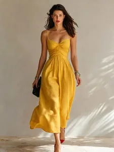 Elegant yellow spaghetti strap pleated maxi dress worn by a model in soft daylight.