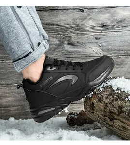 Primo piano di sneaker invernali nere foderate in pile su un tronco di legno innevato