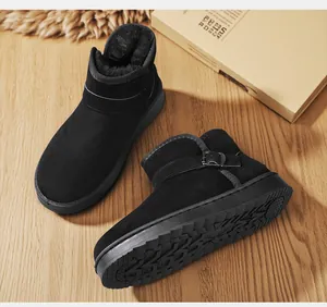 Close-up of black snow boots with fur lining and buckle detail on wooden surface.