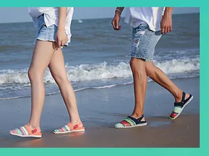 Stel wandelt op strand met kleurrijke geweven slingback sandalen