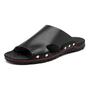 Gros plan de claquettes en cuir noir pour hommes avec rivets et détails rouges.