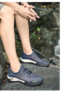 Dettaglio di scarpe da trekking da uomo in mesh traspirante su terreno roccioso