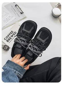 Detailed view of black and grey chunky men's sneakers held against lifestyle props