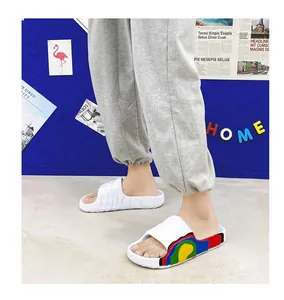 Side detail of white cloud-feeling slides with colorful wavy patterns worn by a model.