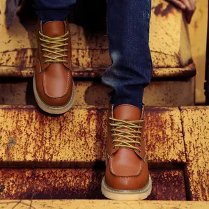 Classic brown leather men's work boots with moc toe stitching on industrial rusty stairs